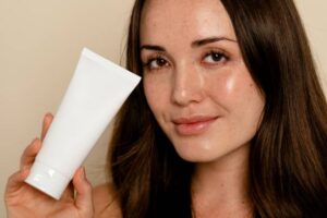 Woman holding face moisturizer tube Overnight Renewal Cream